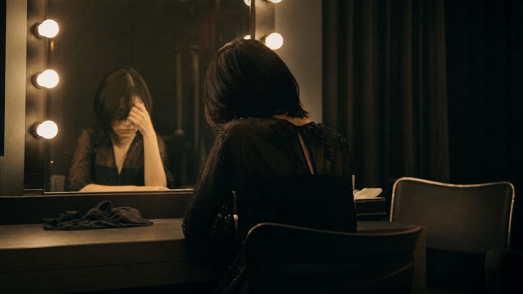 舞台裏の鏡に疲れた姿を映す、ひとりの演者